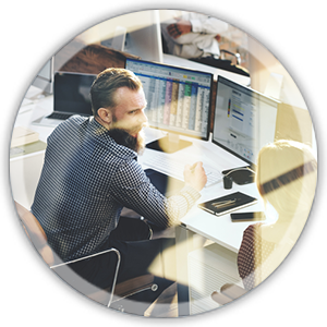 man sitting at a desk working on a computer with multiple screens
